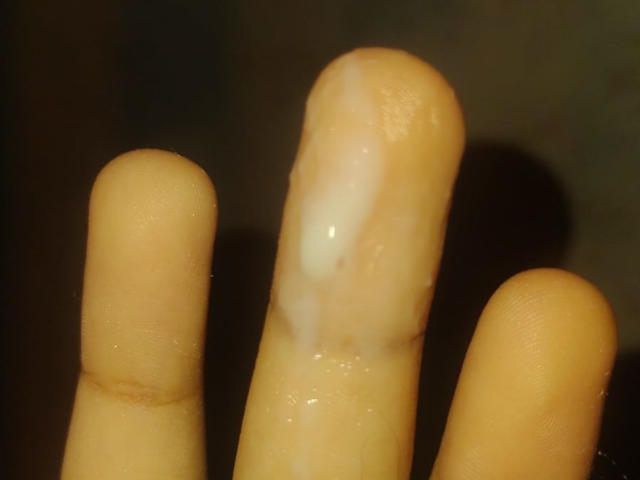 PoarschePink's erect, shiny, cum-covered finger, with two other fingers on either side, in a close-up shot.