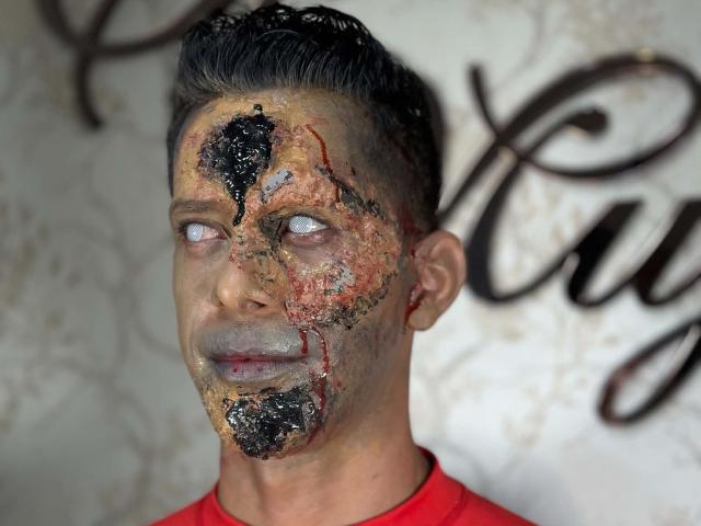 JoseRumBerotop's face is a bloody mess, with black and red grime covering his eyes, nose, and chin, wearing a red shirt, looking up with a grim expression.
