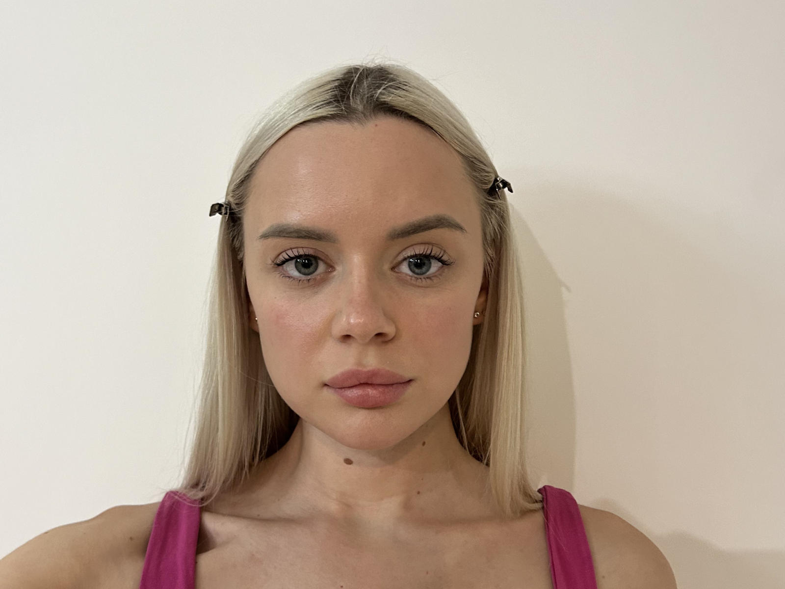 KarrieLav has blonde hair, blue eyes, and pink tank top, with small tits, a cute face, and a slight mole above her pussy. She's staring straight at the camera.