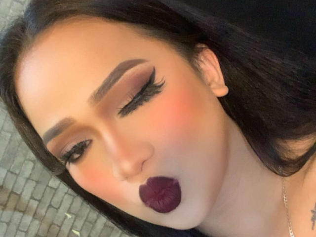 AmaraHugeCock with pouty lips, dark lipstick, and eye makeup, showing off thick, dramatic eyelashes and perfectly shaped eyebrows. She's got long, straight brown hair, too.