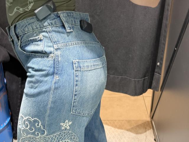 MargoFun's blue denim jeans, showing a tight butt and back pocket, with white embroidery on the lower left and a black belt. Green top visible at waist.