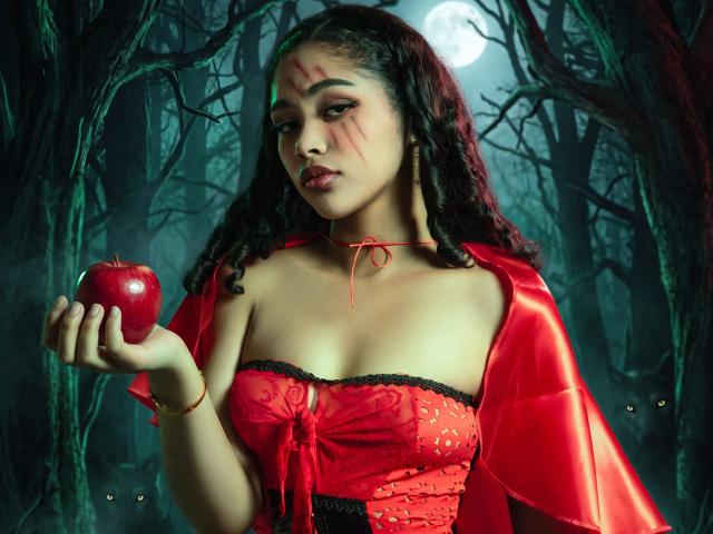FernandaCoa, con cabello rizado oscuro, un corpiño rojo y una capa roja, sosteniendo una manzana roja, rostro marcado por cicatrices, bosque iluminado por la luna, expresión seria, busto mediano, luz suave, arte digital..
