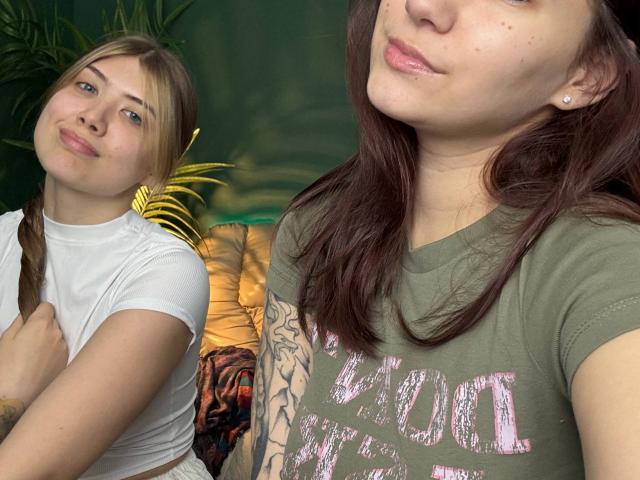 Two HotCaramelsTrios in a photo: one with blonde hair, small tits, white shirt, and pouty lips; another with brown hair, green shirt, tattooed arm, and pink lips.