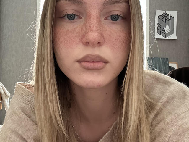 Cathy Bolyard tem pele clara com sardas, cabelo loiro, olhos azuis e lábios rosados, cheios e levemente inchados, vestindo um suéter bege. Suas nádegas não estão visíveis..