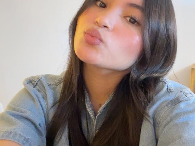 Miia Palmer, con labios carnosos, una camisa vaquera azul y cabello castaño largo, mostrando una expresión ligeramente arrogante y juguetona, como si no le importara nada. Su rostro está sonrojado y está mirando hacia arriba..