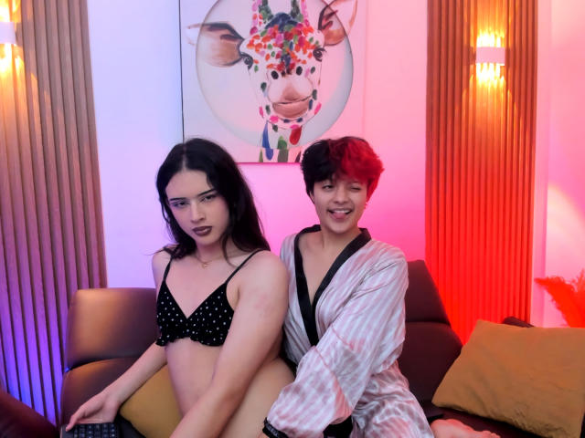 KvsKael with dark hair and small tits in a black polka dot bra, sitting on a couch. KvsKael with red hair and a flaccid penis in a striped robe.