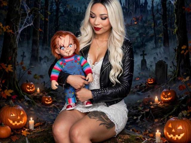 AiunyQueens with long blonde hair, black leather jacket, white lace dress, holding creepy doll with red hair, blue pajamas, and skull face, surrounded by glowing jack-o'-lanterns.