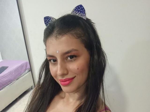 MadissonFontaine has dark hair, pink lipstick, small white dot on her forehead, blue polka-dot cat ears, and a cute smile. Her tits are not visible.