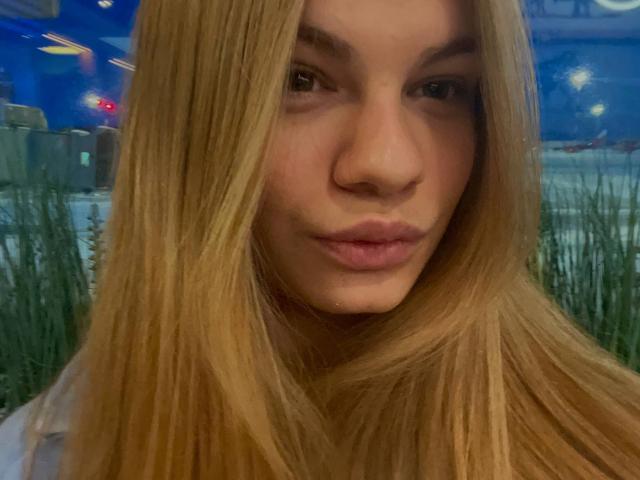 KatherinaHlad has long blonde hair, light skin, and full pink lips, looking directly at the camera with a subtle, confident pout. Her nose is small and her eyebrows are thin.