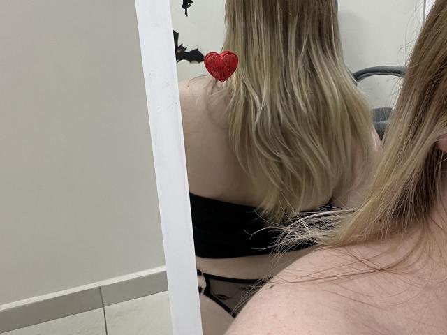 DiLaria staat met haar rug naar een spiegel, waar haar lange blonde haar, een zwarte beha zonder bandjes en zwarte kanten slipjes te zien zijn. Op de reflectie in de spiegel zit een rode hartsticker..