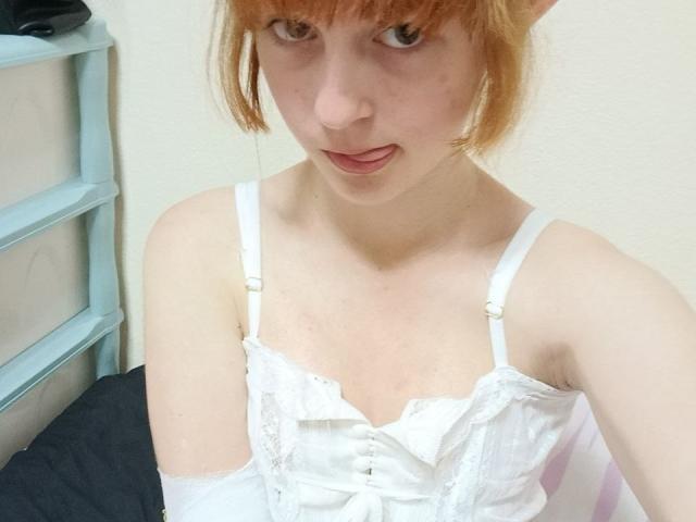 LouieOrner with pale skin, orange hair, and bangs, wearing a white lace-up camisole, looking up with a slightly open mouth, showing a hint of a tongue.
