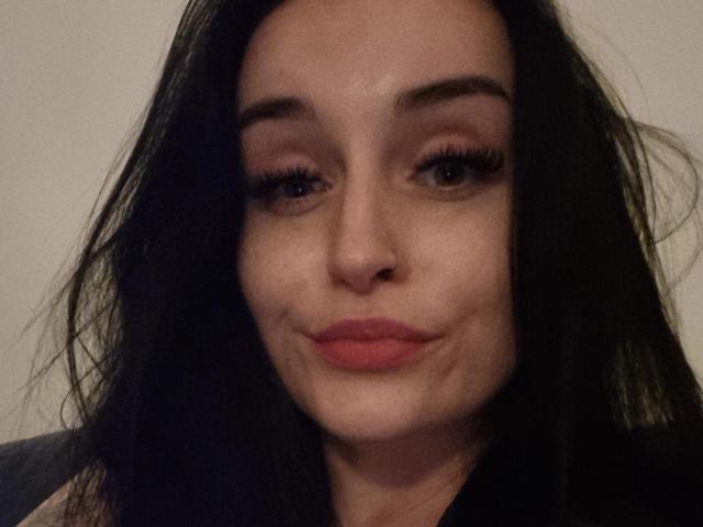Lucy, avec ses cheveux noirs et ondulés, sa peau claire et son rouge à lèvres rouge, affiche un sourire subtil et légèrement retroussé, les yeux à moitié fermés et les longs cils. Son nez est petit et mignon..