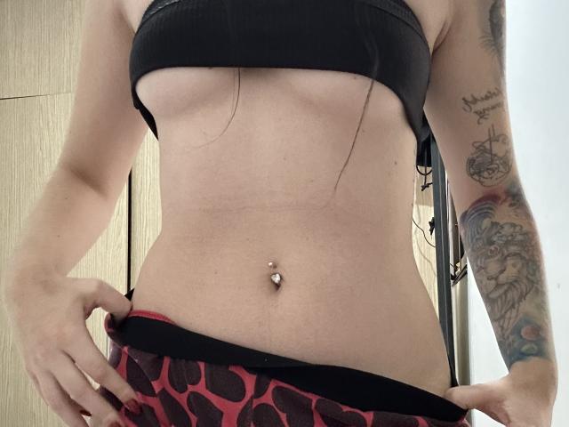 De blote borsten van EvaaFarix, een zwarte sportbeha, een plat buikje, een piercing in de navel, een getatoeëerde arm, het omlaag trekken van rode broek met luipaardprint, waarbij een beetje van haar achterwerk te zien is..