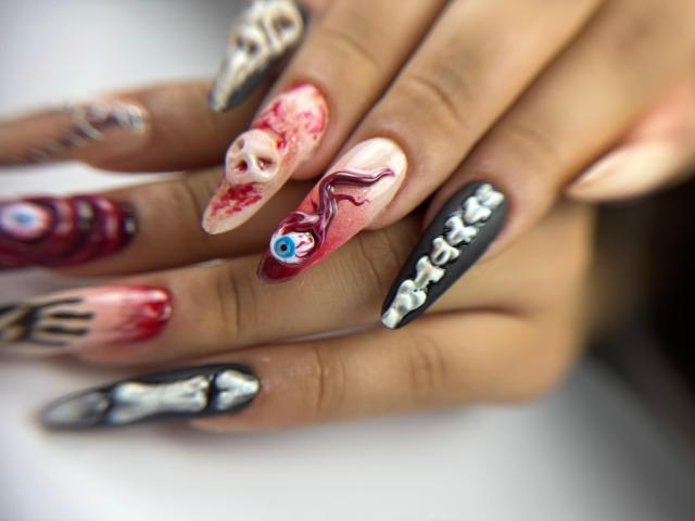 Genesiss's nails are super cute, featuring crazy designs with eyeball, red face, and black with white beads. Her nails are long, sharp, and totally freaky.
