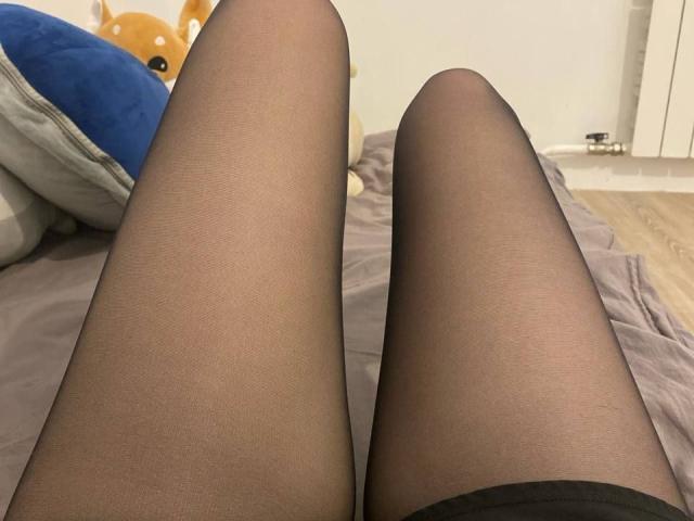 ValeryBazzle's legs in black pantyhose, showing a close-up view from her crotch down, with a stuffed toy and bed in the background.