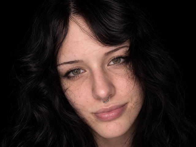 VinitaBartolomei has dark, wavy hair, green eyes, and a nose ring. She's smiling with light freckles on her face, and has subtle pink lipstick.