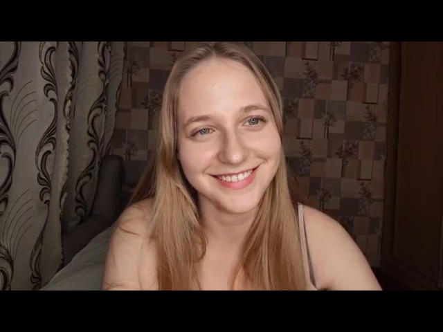 ColettaCorman has long blonde hair, blue eyes, and a smiling face with visible teeth. She's wearing a spaghetti strap top, and her tits are small and cute.