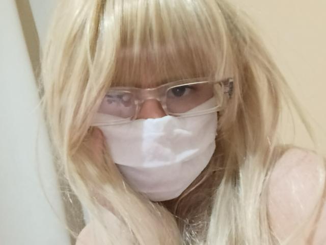 Blonde lanaBink with messy hair, glasses, and white mask, showing only eyes and nose, wearing a sheer top, looking up. Boob outline visible under top.