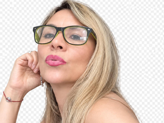 Maytena with blonde hair, pink lipstick, and green-framed glasses, puckering her lips slightly, hand near her face, wearing a red bracelet.