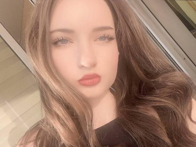LatoshaGuarin has long, wavy brown hair, light skin, and full pink lips with subtle eyeliner and long lashes. She's wearing a black top, looking directly at the camera.