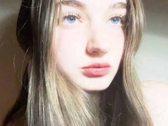 LatoshaGuarin's face with blue eyes, long blonde hair, and pink lips. Her nose is small, and she's looking slightly to the side with a neutral expression.