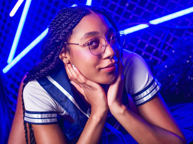 EsmeraldaRoe with braided hair, wearing glasses and a sailor-style top, hands on cheeks, blue neon lights, slightly smiling, dark skin, cute, attractive.