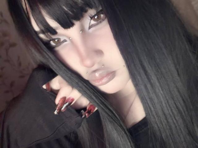AlmaStampka ha i capelli neri, gli occhi marroni e diversi piercing sul viso. Indossa un rossetto scuro e ha le unghie lunghe, appuntite e rosse, decorate con glitter. La sua espressione è seria..