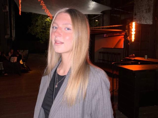Cathy Bolyard heeft lang blond haar, een lichte huid en draagt een grijze jas met strepen over een zwarte top. Ze staat, kijkt iets opzij en heeft een subtiele glimlach..