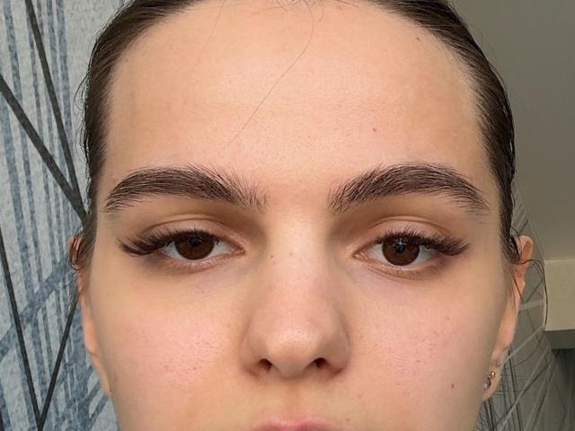 El rostro de Cathryn Lhommedieu, con ojos marrones, cejas pobladas, pestañas largas y un tono de piel ligeramente rosado. Tiene una nariz pequeña y su cabello está recogido..
