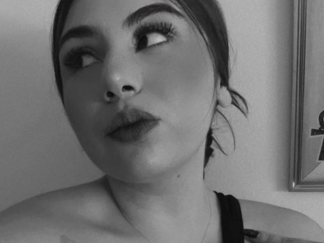 VenusxMusa con viso in scala di grigi, sopracciglia folte, lunghe ciglia e labbra piene che guarda verso l'alto. Indossa una fascia nera e i suoi capelli sono legati indietro. Parte della parte superiore del petto è visibile..