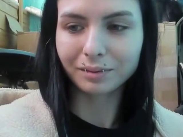 NobukoGraue a les cheveux noirs, une peau claire et plusieurs piercings au visage, notamment un anneau au septum et des piercings sur la lèvre inférieure. Elle porte une veste blanche duveteuse et regarde légèrement sur le côté..