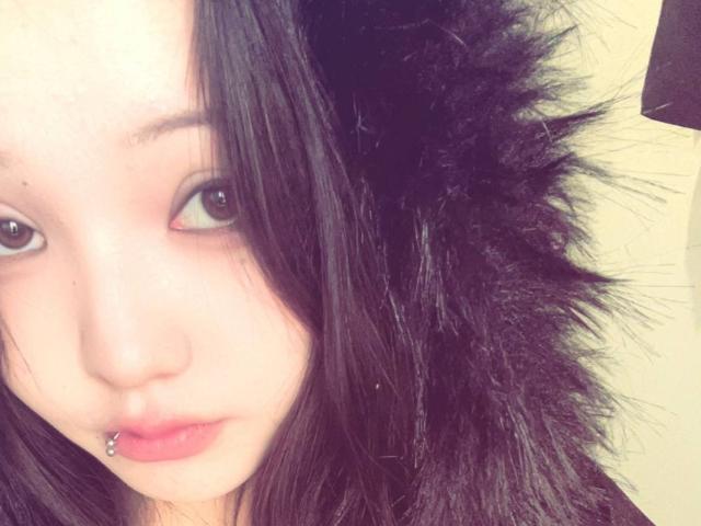 RayeAbend with pale skin, black messy hair, brown eyes, and a pierced lower lip showing a silver ball. Soft, almost blank expression. Fuzzy hair on the right side.