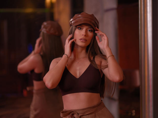 AuroraDuval with brown bra, tied brown pants, brown cap, long brown hair, hands in cap, gold bracelet, mirror reflection, soft brown lighting, sexy, attractive, slim, small tits.