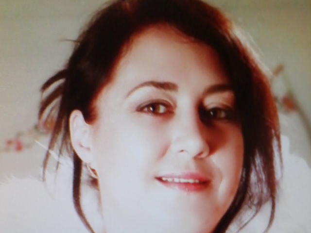 Eine verführerische, wohlgeformte Frau mit braunen Haaren, heller Haut, einem kaum sichtbaren Lächeln, einem leicht unscharfen Gesicht und einer sichtbaren, kleinen Nase, die keine Kleidung trägt, in einem weich beleuchteten Bild..