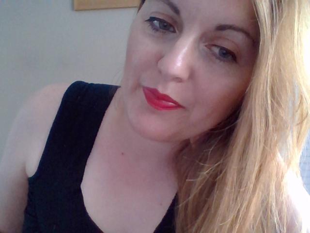 FrenchLea ha la pelle chiara, i capelli biondi, il rossetto rosso, una canotta nera e un leggero sorriso. Sta guardando la fotocamera con gli occhi azzurri. Il suo seno non è visibile..