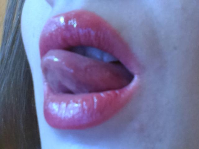 Le labbra rosa e lucide di Victoria's Secret sono leggermente aperte, con la lingua che tocca la parte superiore dei denti. La sua pelle blu contrasta con le sue labbra rosa e lucide..