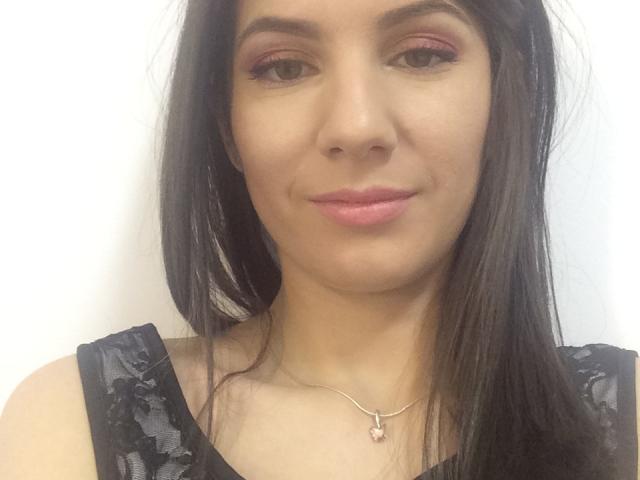 LanyJolene has brown eyes, pink eyeshadow, pink lipstick, and a silver necklace with a pink heart. She's wearing a black lace top, and has straight black hair.