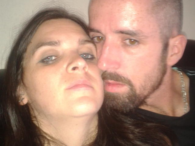 Een selfie van SexiCouple, met een kale, baardige man die leunt voor een vrouw met bruin haar en blauwe ogen. Zijn neus raakt bijna haar gezicht..