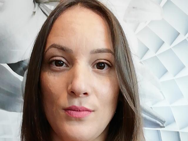 QueenKaly's face with brown eyes, pink lips, and straight brown hair. She has a slight pout and her nose is centered in the image.