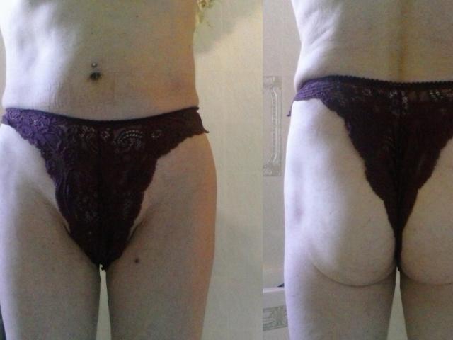 A pele clara de Hermeline, vestindo uma calcinha de renda escura, mostrando seu bumbum e sua vulva da frente e de trás. Ela tem um piercing no umbigo e uma pequena pinta escura no lado esquerdo..