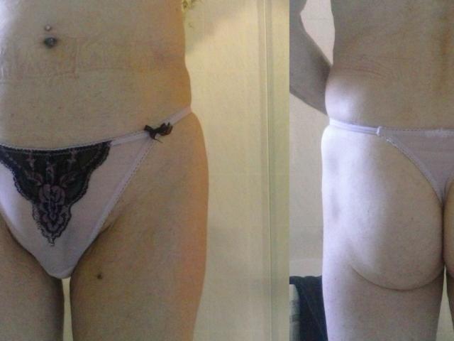 Hermeline's lichtroze onderbroek met zwarte kant heeft een klein strikje, en toont haar zachte, licht ronde billen en een piercing in haar navel, weergegeven in een spiegelbeeld..