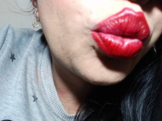 LuluFrançaises volle, rote Lippen sind der Mittelpunkt, kombiniert mit einem grauen Hemd und einem einzelnen Stern auf der linken Seite, sowie einem kleinen Ohrring, der auf der rechten Seite sichtbar ist..