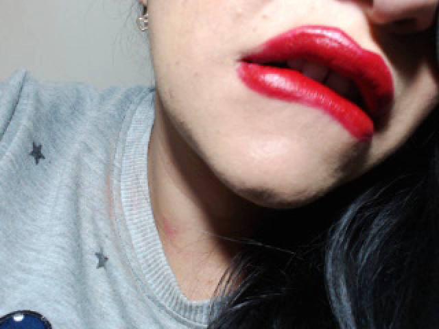 LuluFrancaise's red, glossy lips are slightly open, showing a hint of teeth. She's wearing a gray shirt with small star patterns, and has black hair.