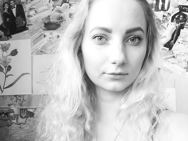 JillFox ha la pelle chiara, i capelli biondi ondulati e gli occhi azzurri, e guarda direttamente la fotocamera con un'espressione neutra. I suoi piccoli seni sono leggermente visibili. Autoscatto in bianco e nero..