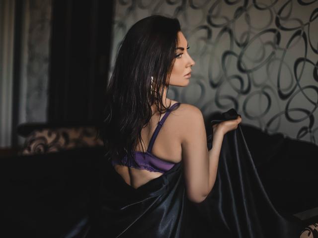 TellySabe com cabelo escuro, sutiã roxo e costas nuas, segurando seda preta, vista lateral, sexy, iluminação suave, cabelo levemente molhado, elegante, maquiagem discreta..