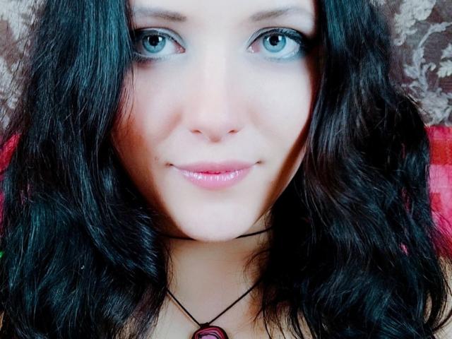 SweetttAngel ha gli occhi azzurri, i capelli neri ondulati e un leggero sorriso con labbra rosa lucide. Indossa una collana nera con un ciondolo rosso. Le sue natiche non sono visibili..
