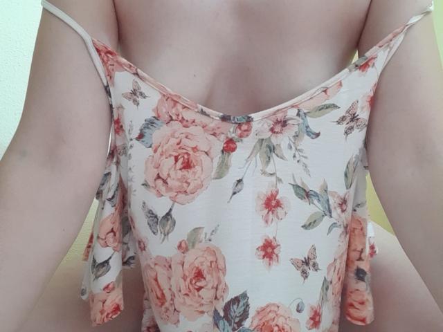 Xxandra's floral top, pulled down to reveal her pale, flat, small-ass, and bare, soft, white tits, with thin straps falling off her shoulders.