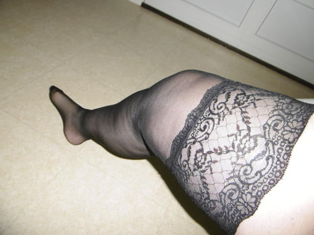 LiliChattePoilue's leg is raised, wearing black lace stockings that show her thigh and foot. The lace pattern is intricate and she's on a tiled floor.