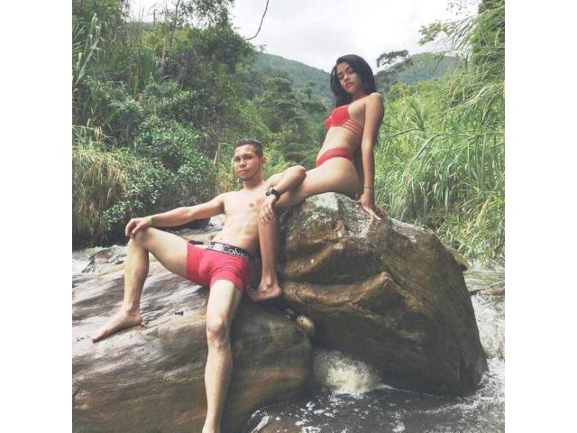 Stefany et Juan, avec de petites seins et des cheveux noirs, portant un bikini rouge, sont assises sur un rocher, tandis que Juan, avec des fesses de taille moyenne et des cheveux bruns courts, portant un short rouge, est assis en dessous..