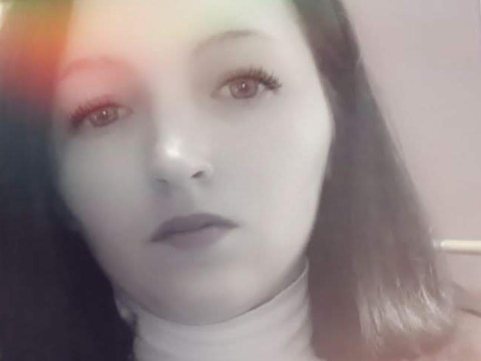 En la foto se ve el rostro de SallyXSweet, con piel pálida, lápiz labial oscuro y pestañas largas. Tiene el cabello oscuro de longitud media y lleva un pañuelo blanco..
